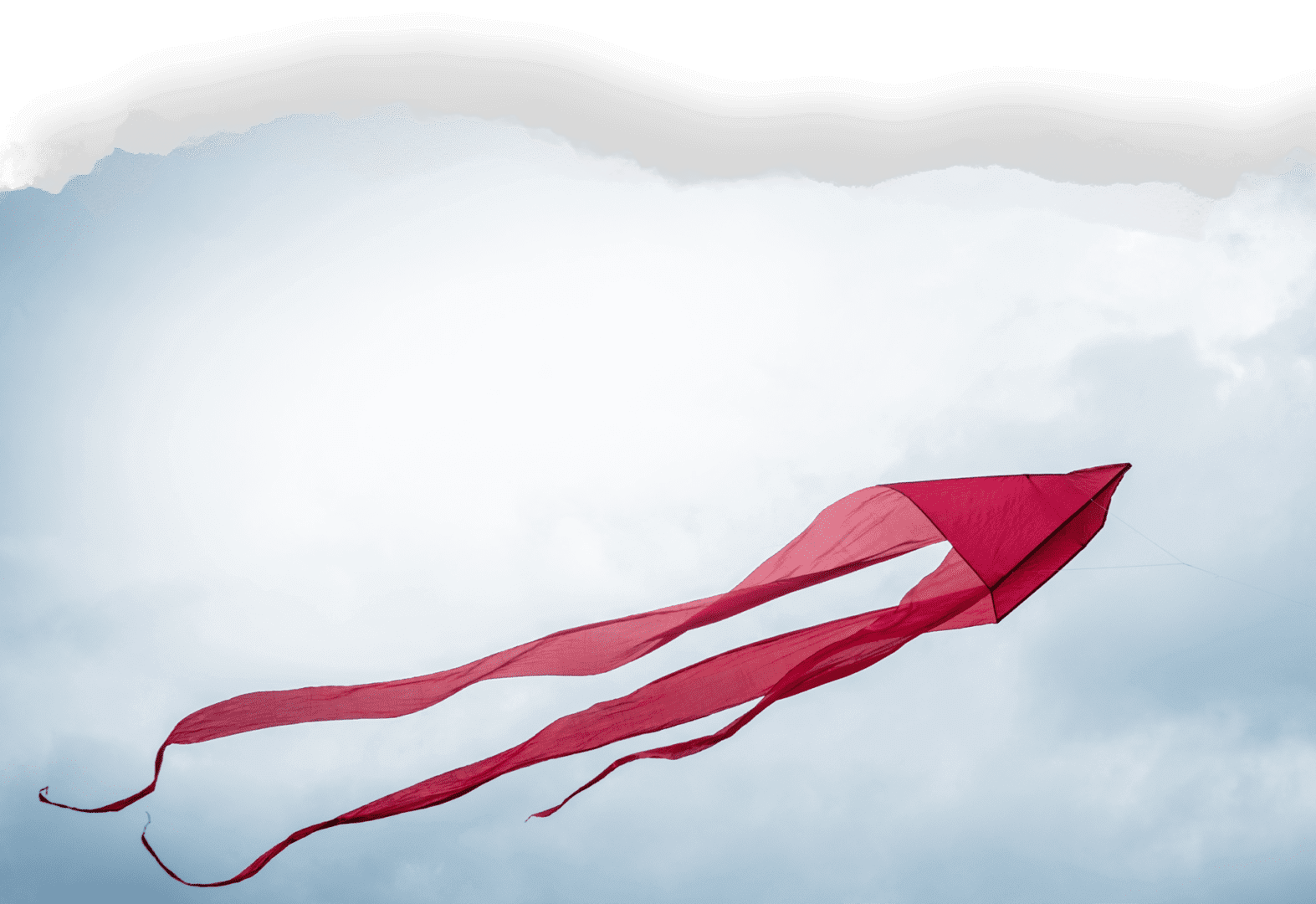 Large red kite flying in a cloudy blue sky